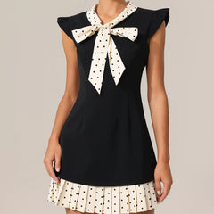 Black dress with a white polka dot bow and skirt on a neutral background