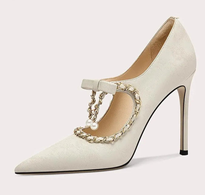 White high-heeled shoe with gold chain detail on a white background