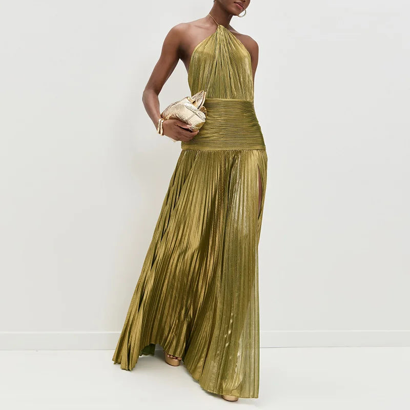 Woman wearing a gold pleated dress holding a clutch against a white background