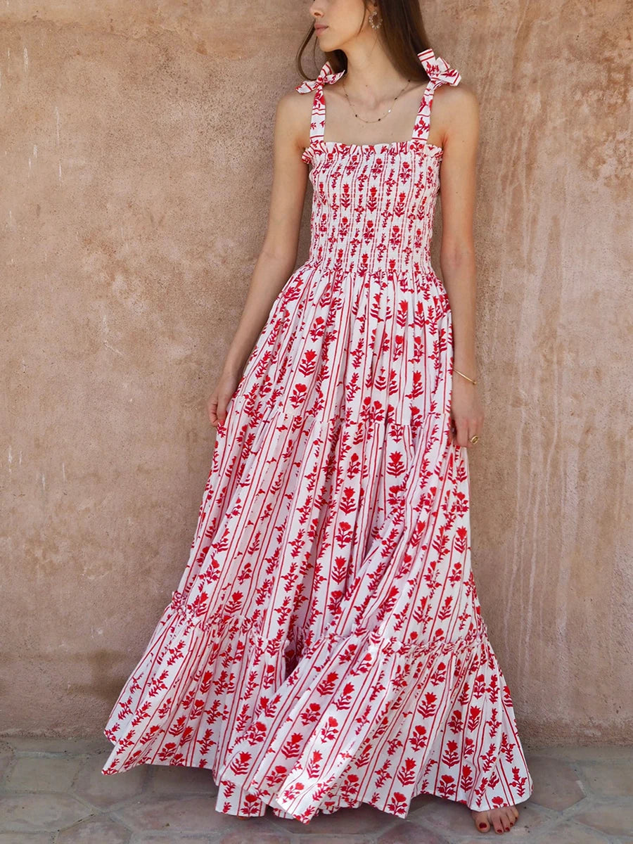 Woman wearing a red and white floral dress against a beige wall.