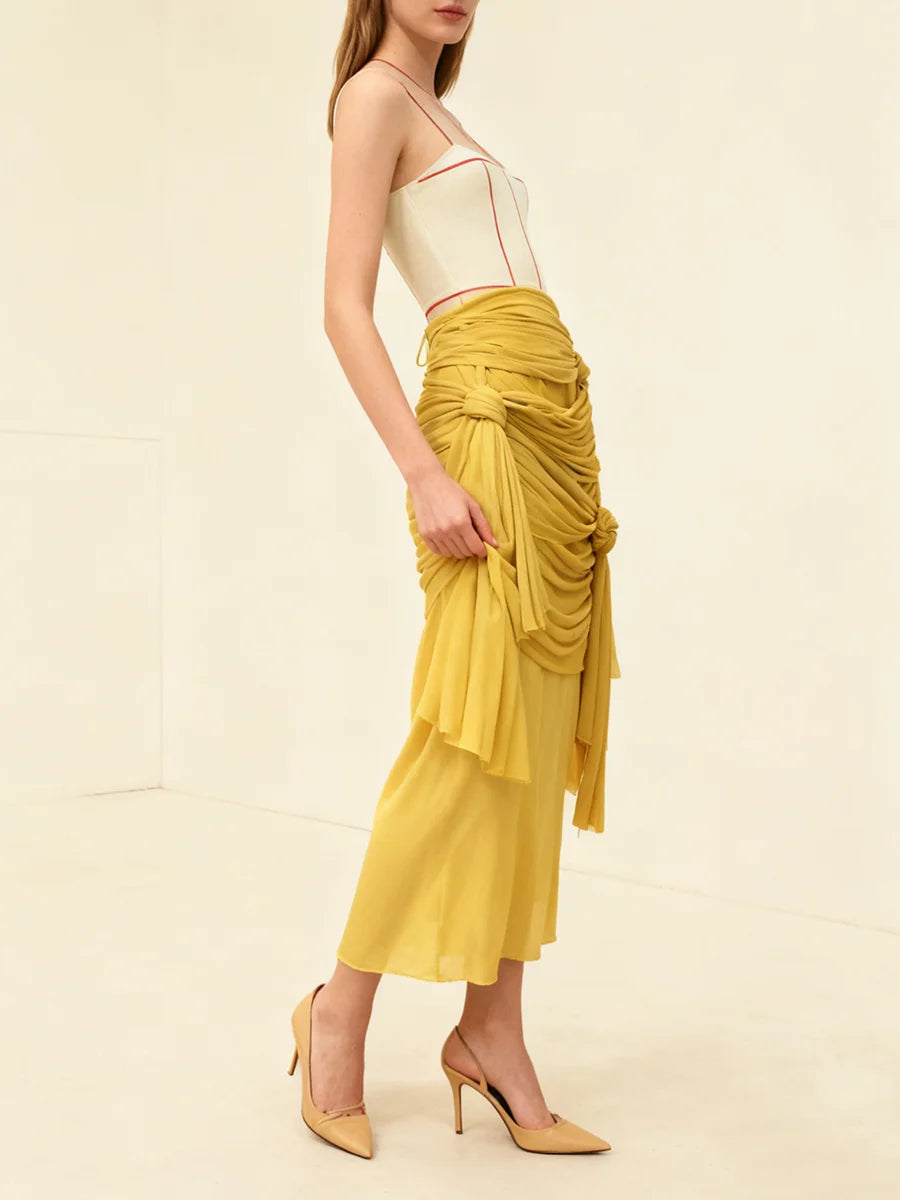 Woman wearing a yellow ruched skirt with a white top on a beige background