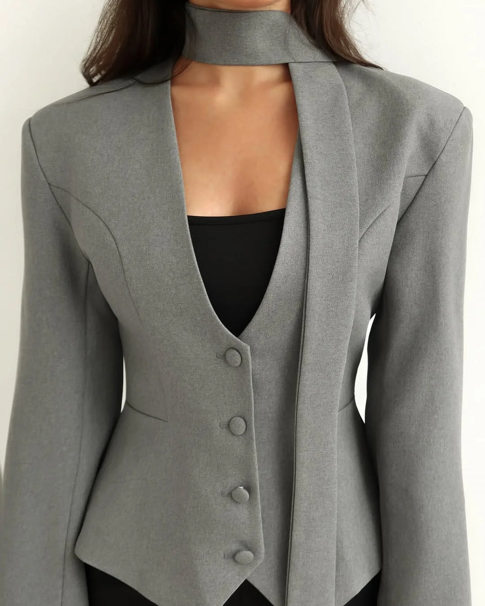 Gray blazer with a black top underneath on a white background