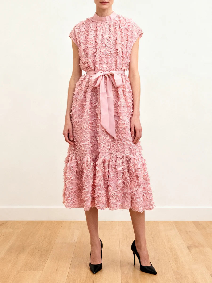 Woman wearing a pink floral dress with a belt on a white background