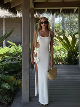 Woman in a white dress with floral embellishments standing outdoors.