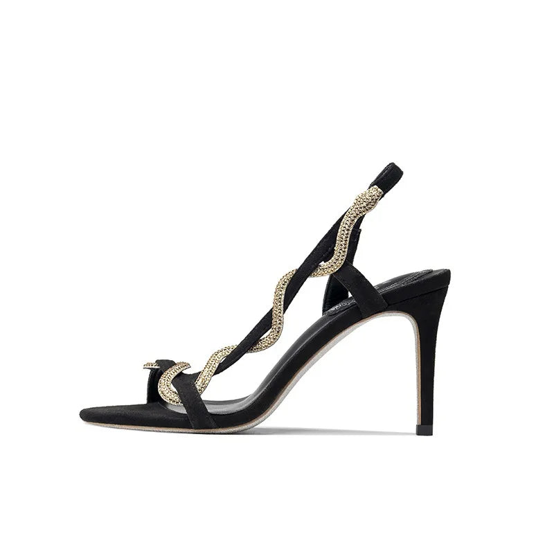 Profile view of black stiletto sandals showcasing the high heel and rhinestone detail.
