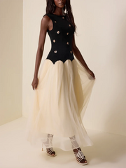 Woman wearing a black bodice with gold embellishments and a beige skirt on a plain background