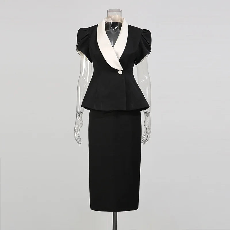 Black peplum blazer with white contrast lapels and a black midi skirt displayed on a mannequin.