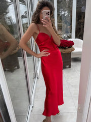 Woman in a red dress taking a mirror selfie in an outdoor setting.