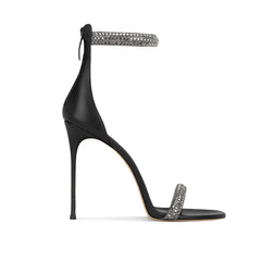 Black high-heeled sandal with decorative ankle strap and toe ring on a white background