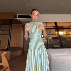 Woman wearing a green and white striped dress in a room with furniture and decor.