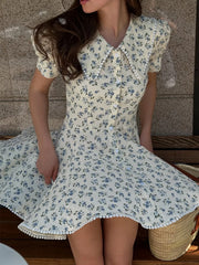 Woman wearing a floral dress sitting on a wooden bench.