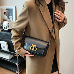 Person holding a black handbag with a gold clasp in a room setting.