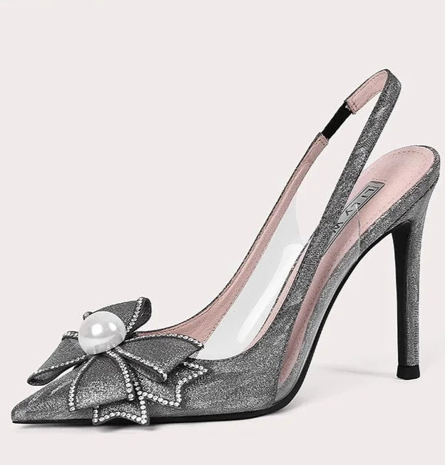 High-heeled shoe with decorative bow and pearl on a light pink background