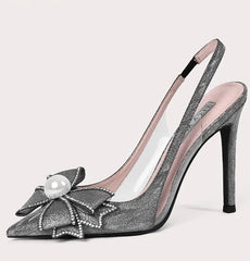High-heeled shoe with decorative bow and pearl on a light pink background