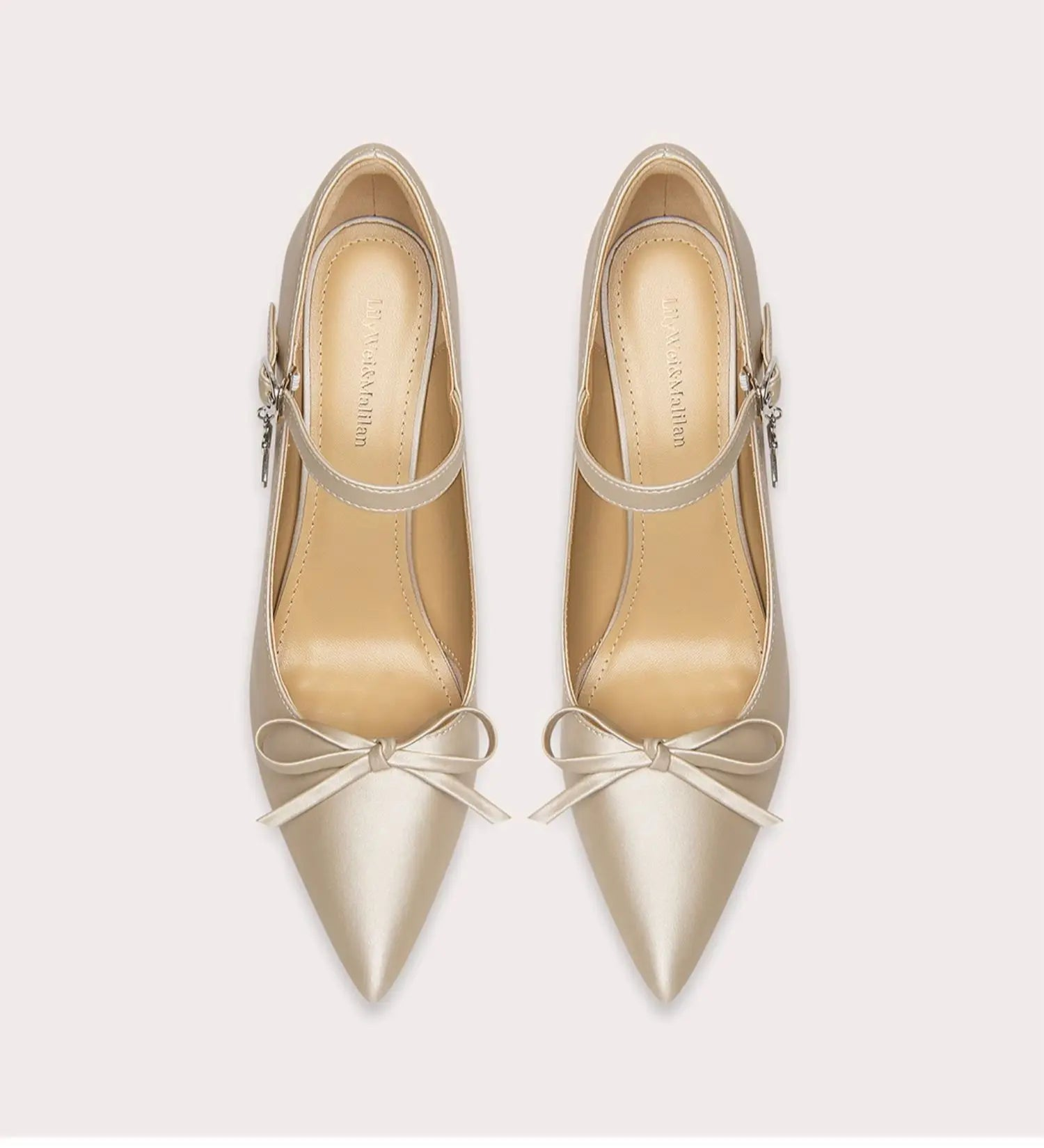 Pair of beige high-heeled shoes with bow details on a light gray background