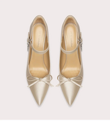 Pair of beige high-heeled shoes with bow details on a light gray background
