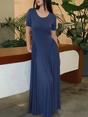Woman wearing a blue dress standing in an indoor setting with plants.