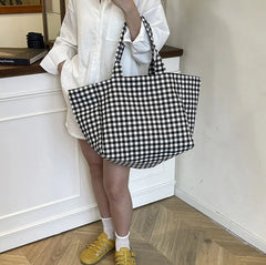 Person holding a black and white checkered bag in a room with wooden flooring.