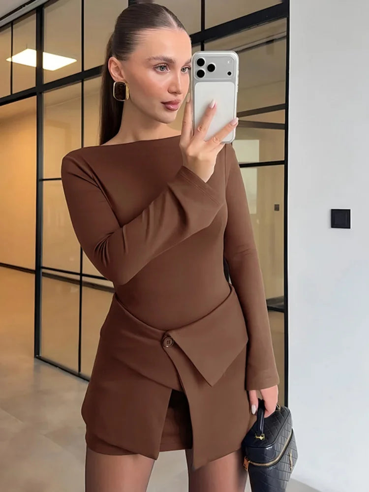 Woman in a brown dress taking a mirror selfie in an indoor setting.