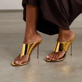 Gold patent thong heels on a model's feet.