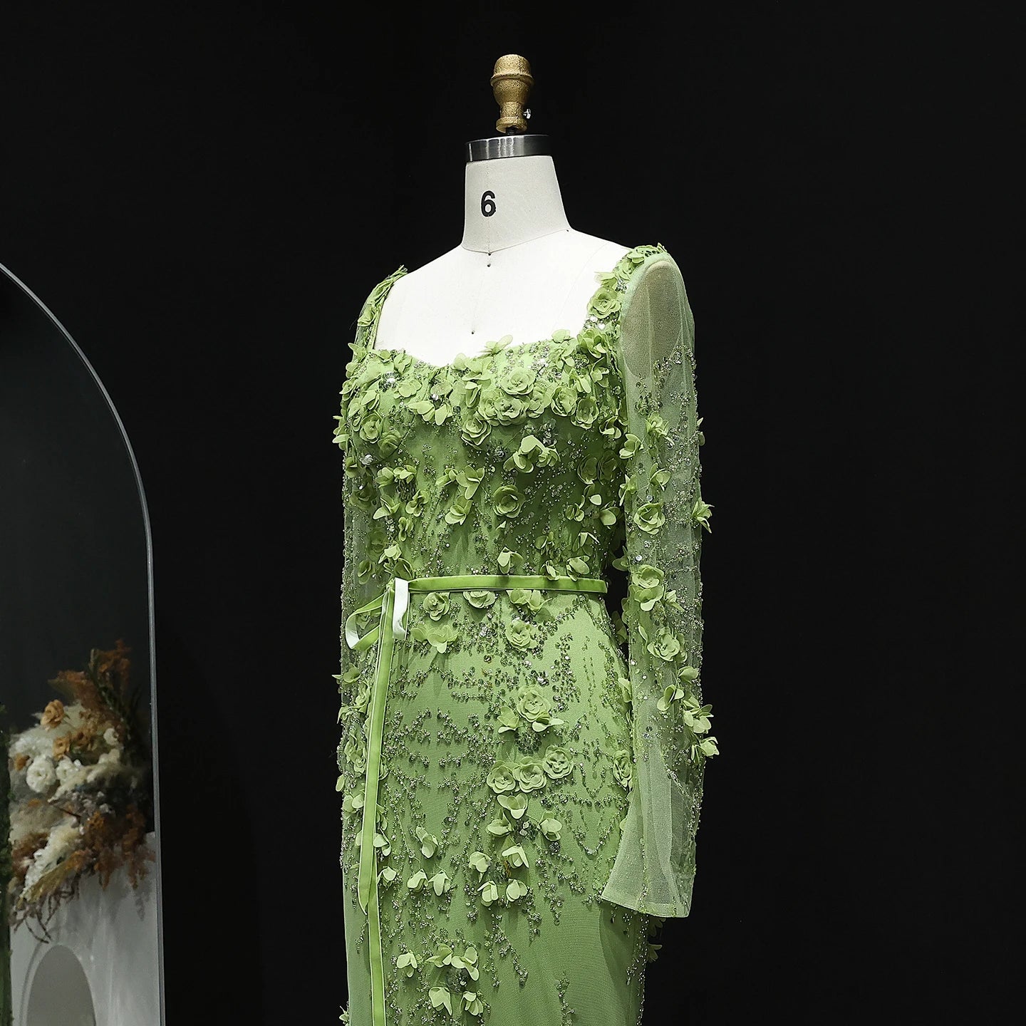 Green floral dress on a mannequin against a black background