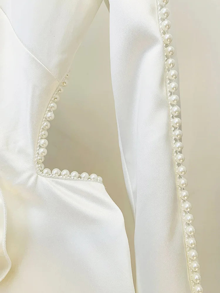 Close-up of a white garment with pearl detailing on a beige background