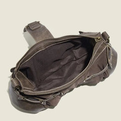 Brown leather bag with a visible zipper on a beige background