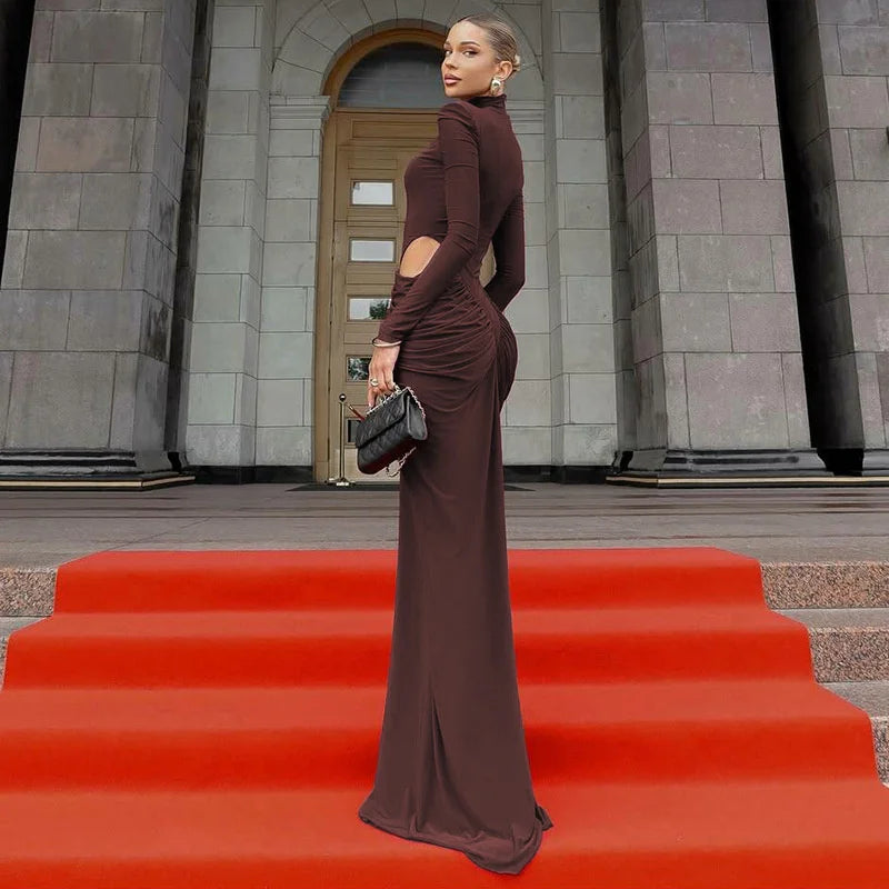 Woman in a brown evening gown standing on a red carpet in front of a building entrance.