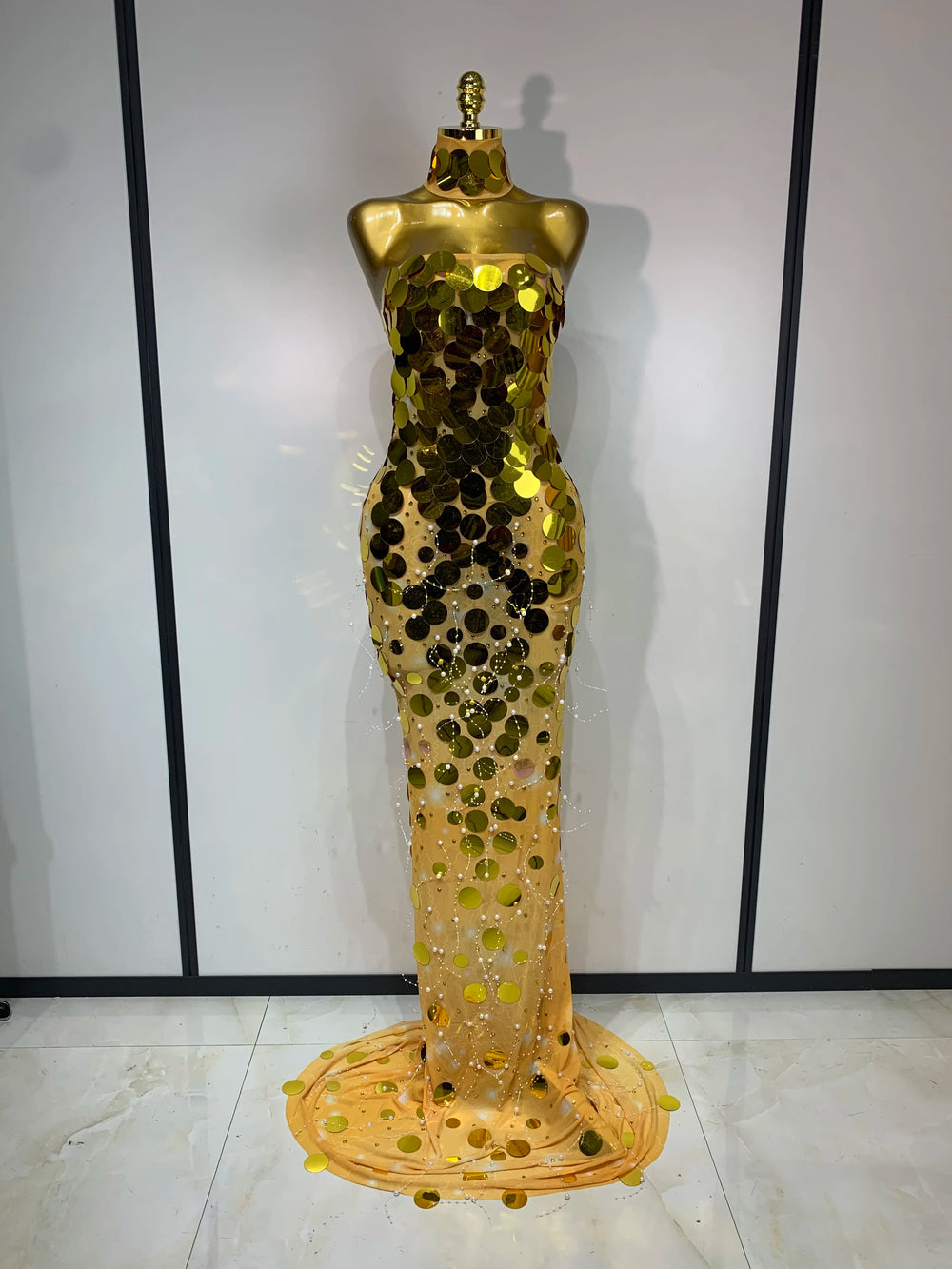 Mannequin wearing a gold sequin evening gown against a white background