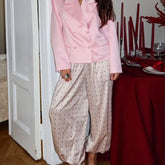 Person wearing a pink outfit with polka dot pants standing near a dining table.