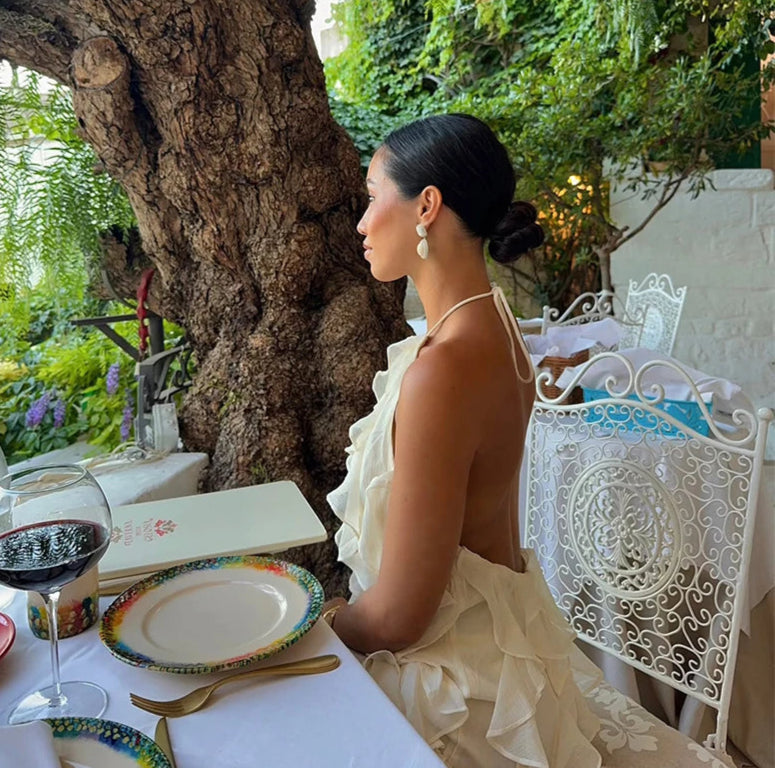 Woman sitting at an outdoor dining table with a scenic background