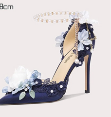 Navy blue high-heeled shoe with floral and pearl details on a white background