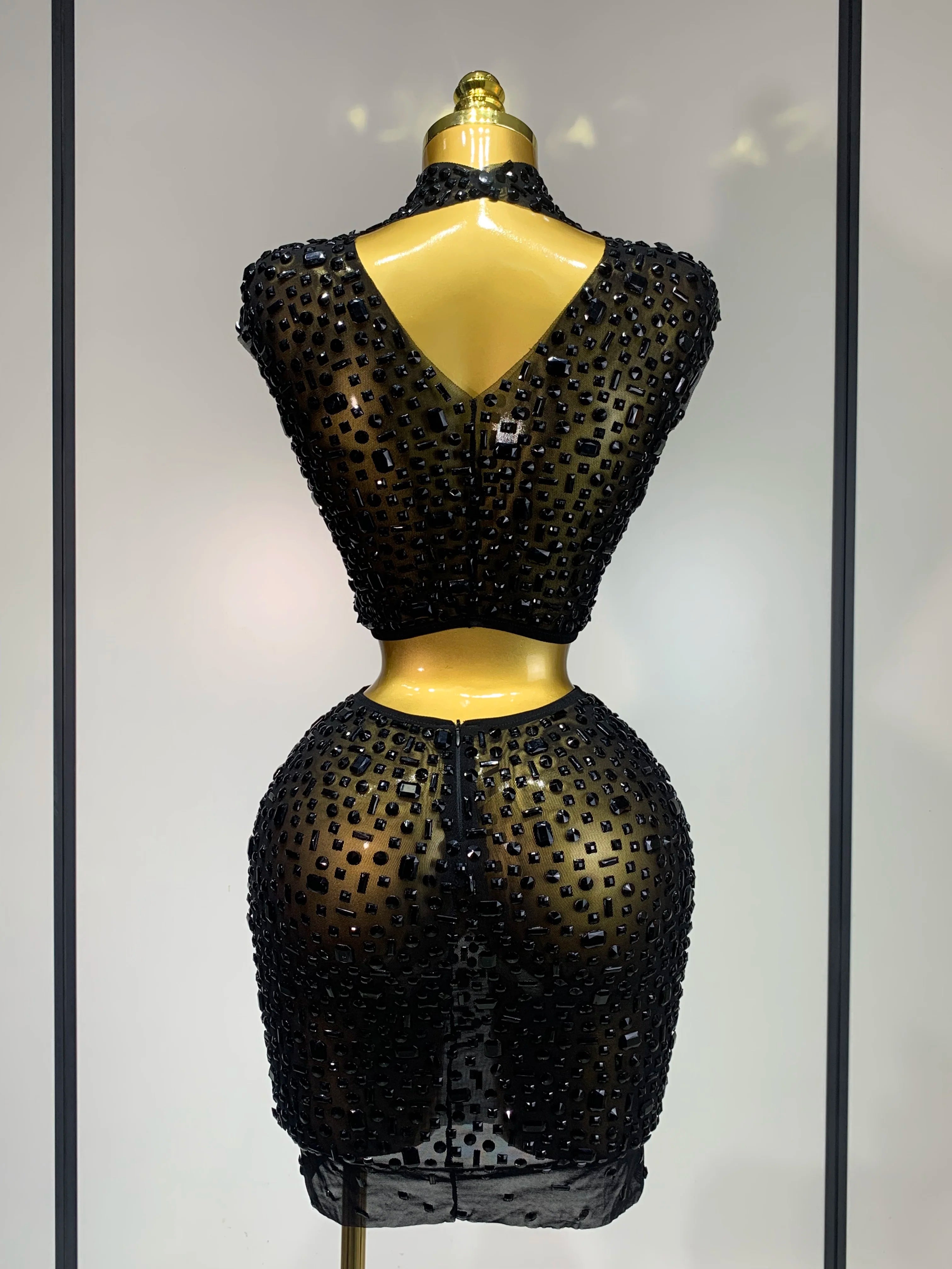 Black beaded dress on a mannequin against a neutral background