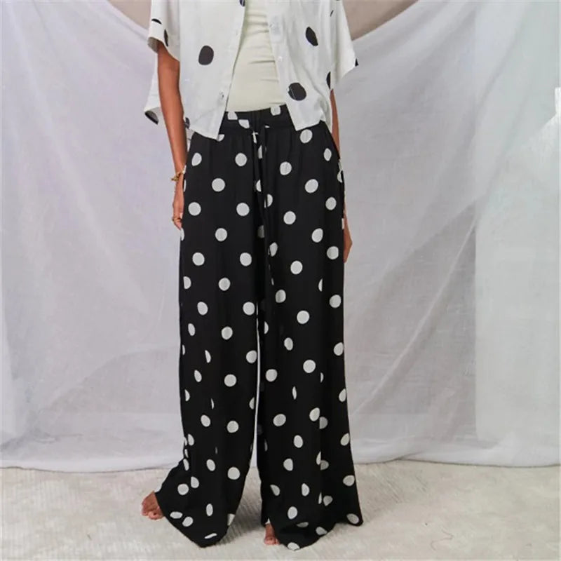 Model wearing black polka dot wide leg palazzo pants and a short sleeve top
