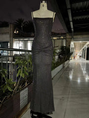 Black sequin evening gown on a mannequin in an outdoor setting with plants and building in the background.