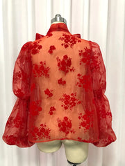 Red floral lace top on a mannequin against a white curtain background