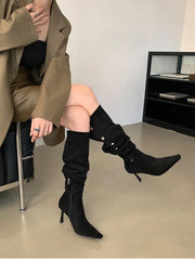 Person wearing black knee-high boots sitting on a chair indoors.