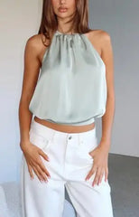 Woman wearing a light green halter top and white pants against a neutral background