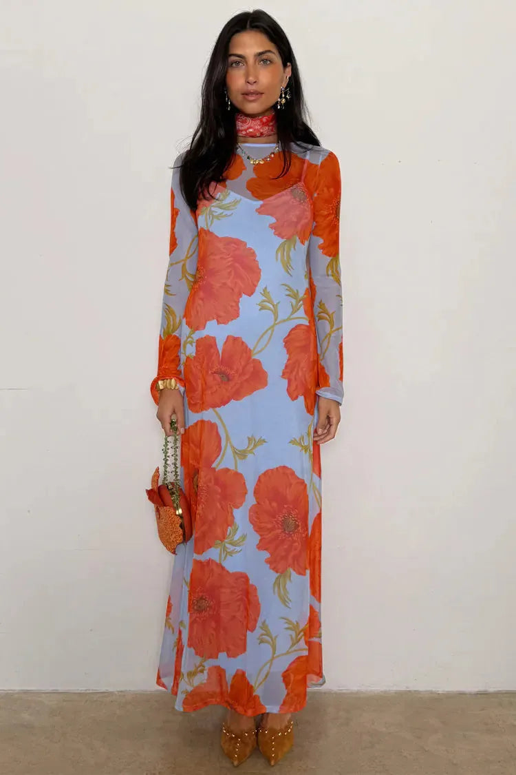 Woman wearing a long floral dress with orange and red flowers on a plain background