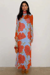 Woman wearing a long floral dress with orange and red flowers on a plain background
