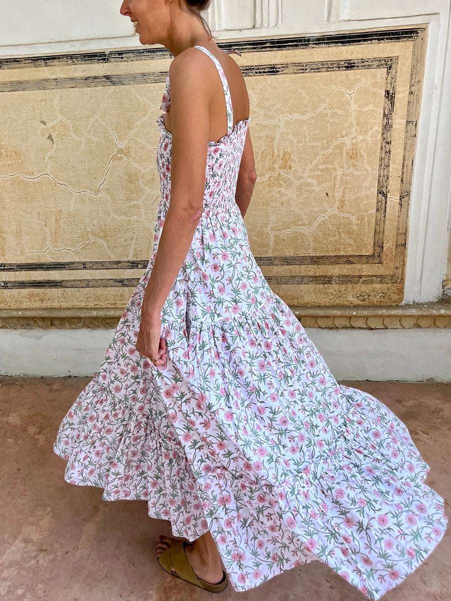 Woman wearing a floral dress standing in front of a decorative wall.