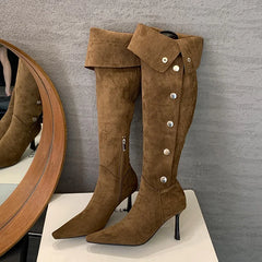 Brown suede knee-high boots with button details on a gray background