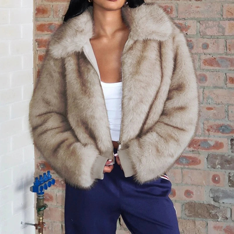Person wearing a beige fur coat in front of a brick wall.