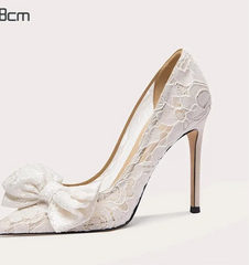 White lace high-heeled shoe with a bow on a light gray background