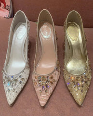 Three high-heeled shoes with embellishments on a brown surface