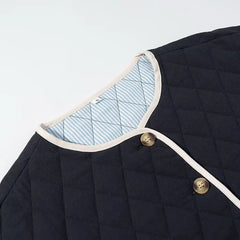 Navy quilted jacket with white trim and gold buttons on a light gray background