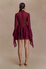 Maroon dress with ruffled layers on a beige background