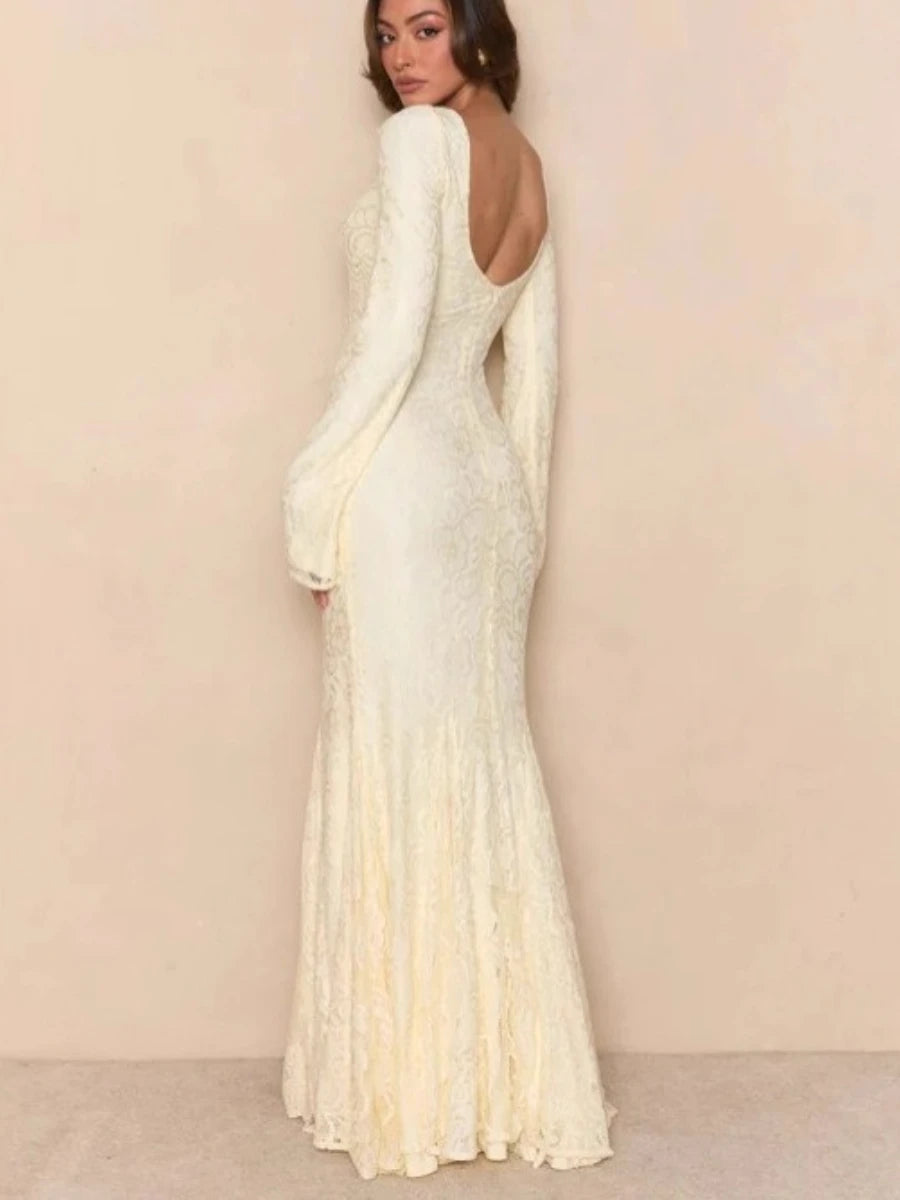 Woman wearing a white evening gown with long sleeves against a beige background