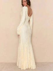 Woman wearing a white evening gown with long sleeves against a beige background
