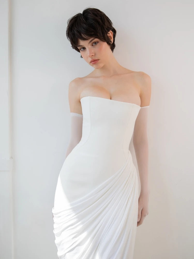 Woman wearing a strapless white wedding dress against a plain background